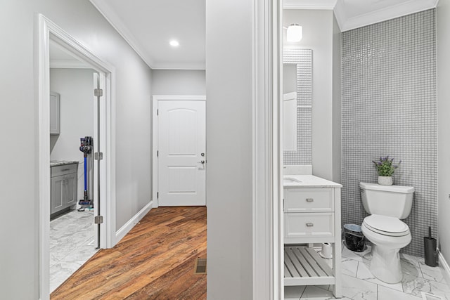 bathroom with wood-type flooring, vanity, toilet, and ornamental molding