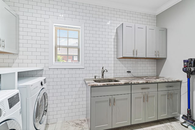 washroom featuring cabinets, crown molding, sink, tile walls, and washing machine and clothes dryer