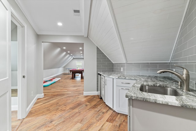 kitchen with sink, light hardwood / wood-style flooring, vaulted ceiling with beams, light stone countertops, and pool table