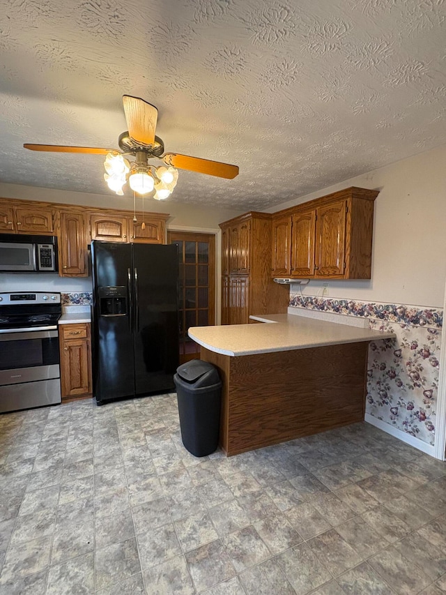 kitchen with kitchen peninsula, ceiling fan, stainless steel appliances, and a textured ceiling