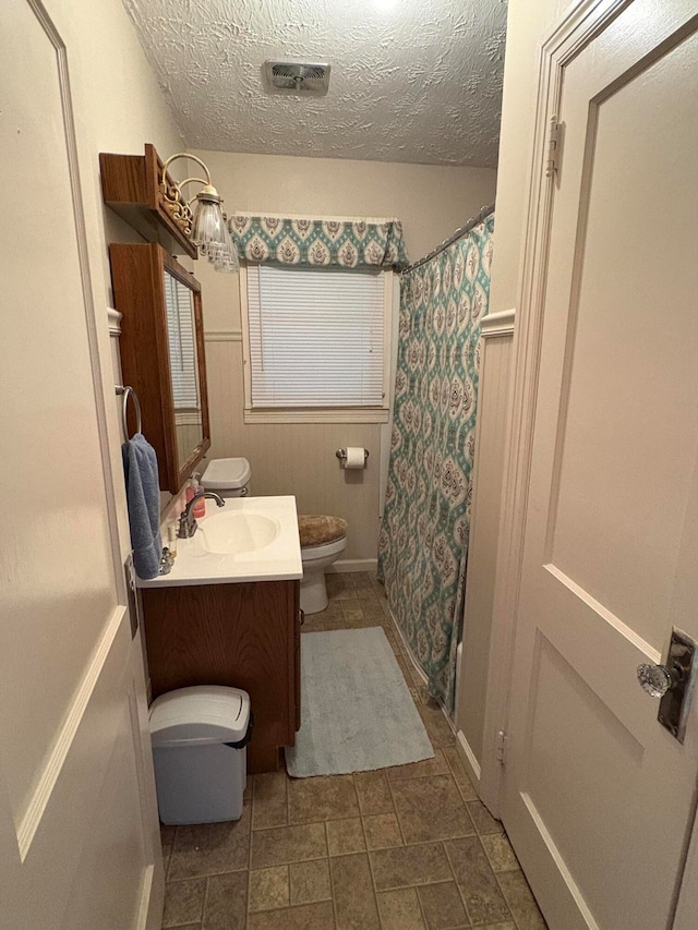 full bathroom featuring vanity, toilet, a textured ceiling, and shower / tub combo with curtain