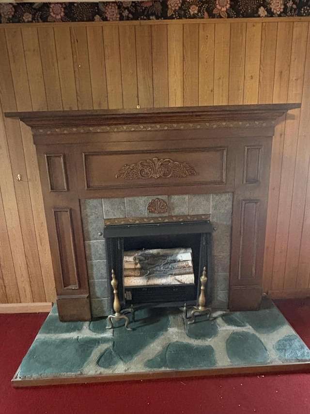 room details featuring wood walls and a tiled fireplace