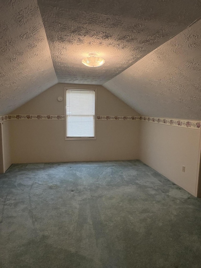 bonus room featuring lofted ceiling, carpet floors, and a textured ceiling