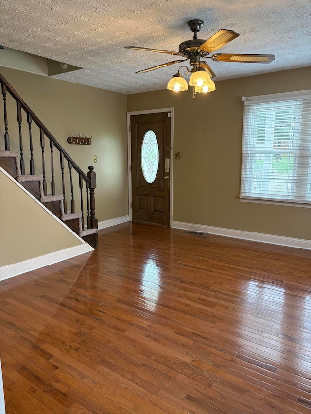 foyer entrance featuring a textured ceiling, ceiling fan, and dark hardwood / wood-style floors