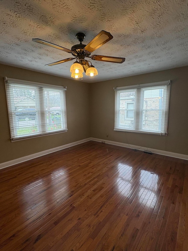 empty room featuring a textured ceiling, ceiling fan, and dark wood-type flooring