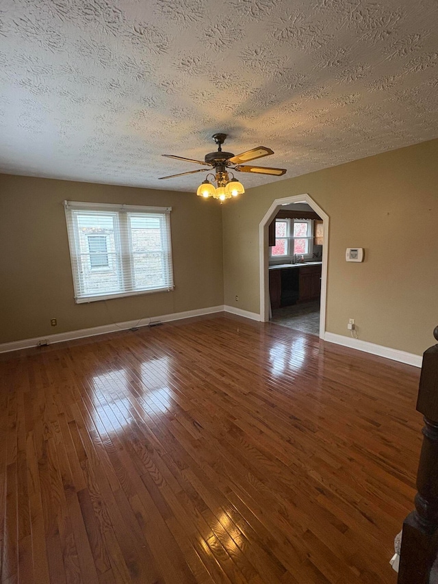 unfurnished living room featuring a healthy amount of sunlight, dark wood-type flooring, and a textured ceiling