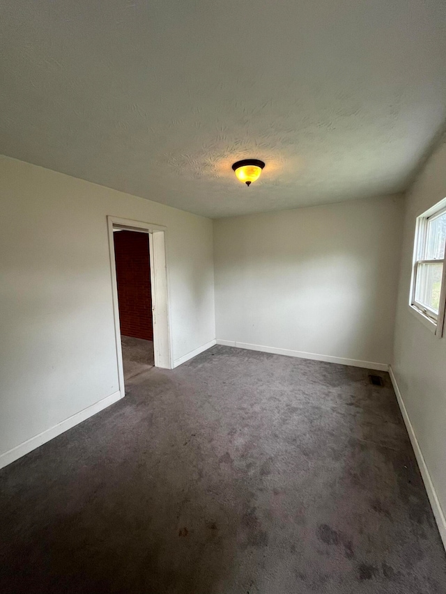 carpeted spare room featuring a textured ceiling