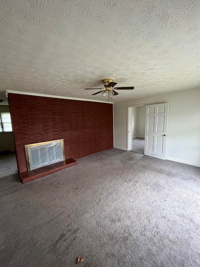 carpeted spare room with ceiling fan, a large fireplace, and a textured ceiling