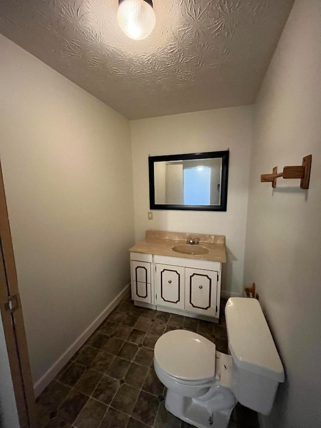 bathroom with tile patterned flooring, vanity, toilet, and a textured ceiling