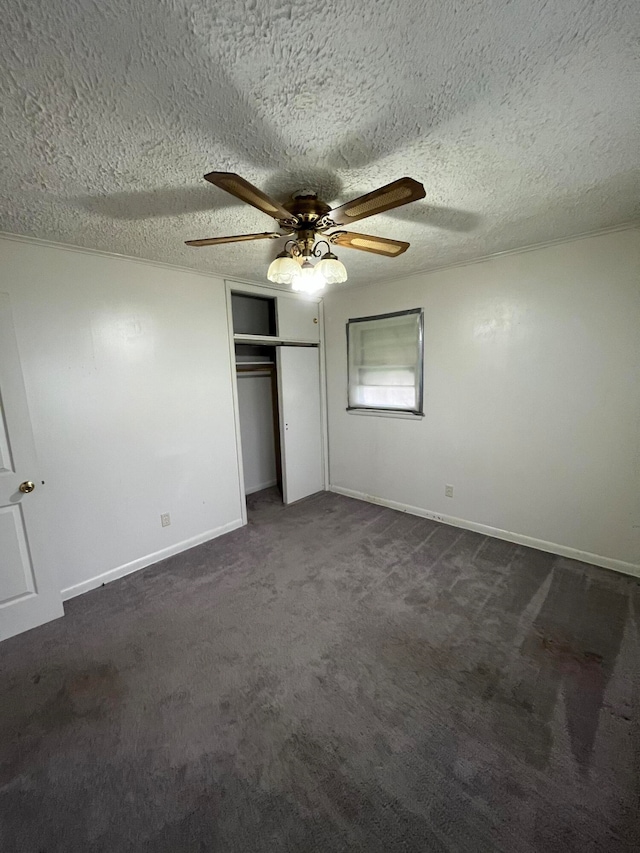 unfurnished bedroom with ceiling fan, dark carpet, a textured ceiling, and a closet