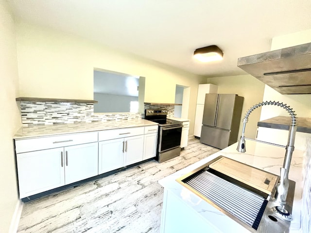 kitchen featuring light stone counters, light hardwood / wood-style floors, decorative backsplash, white cabinets, and appliances with stainless steel finishes