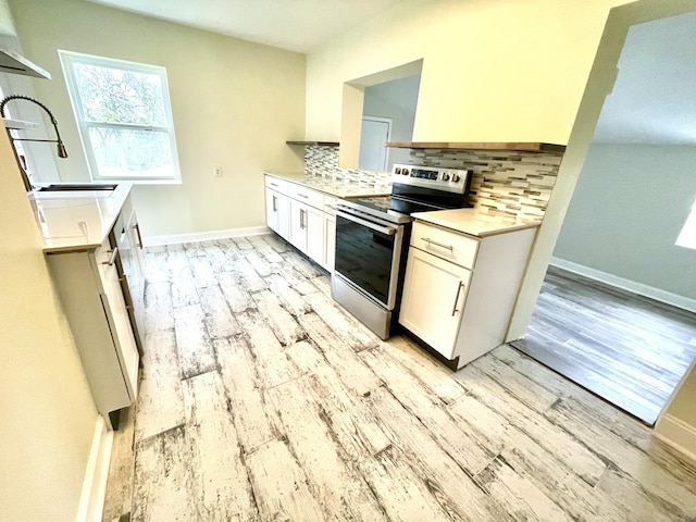 kitchen featuring backsplash, white cabinets, sink, light hardwood / wood-style flooring, and stainless steel electric range oven