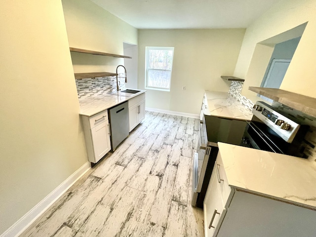 kitchen with white cabinets, sink, light hardwood / wood-style flooring, decorative backsplash, and appliances with stainless steel finishes