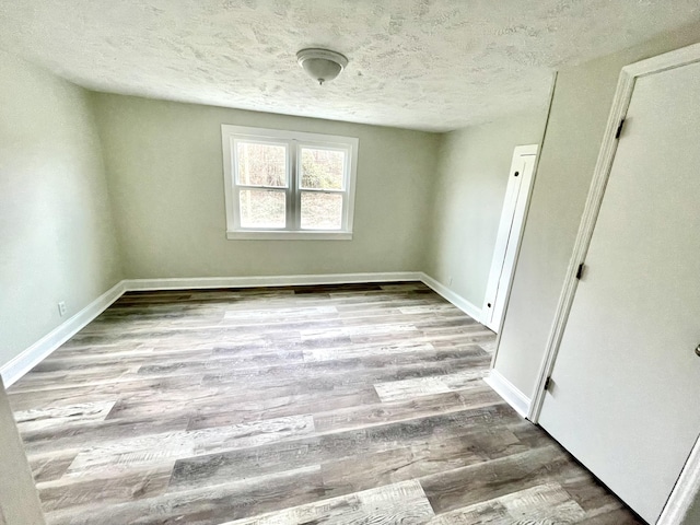 unfurnished room featuring light wood-type flooring and a textured ceiling