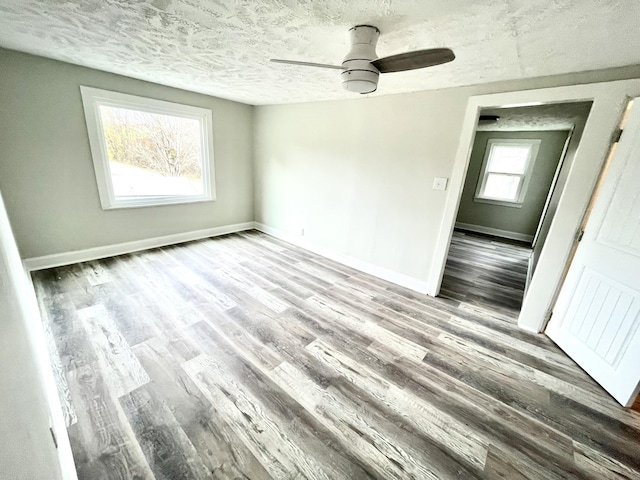 unfurnished room featuring hardwood / wood-style flooring, ceiling fan, a healthy amount of sunlight, and a textured ceiling