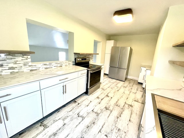 kitchen featuring backsplash, white cabinets, light stone counters, kitchen peninsula, and stainless steel appliances