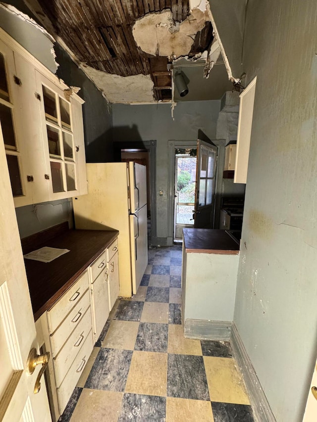 kitchen featuring cream cabinets, white refrigerator, and wooden ceiling