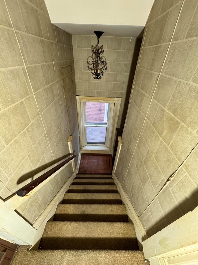 stairs with a notable chandelier