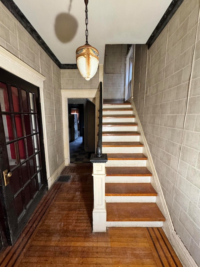 stairway featuring hardwood / wood-style floors, tile walls, and crown molding