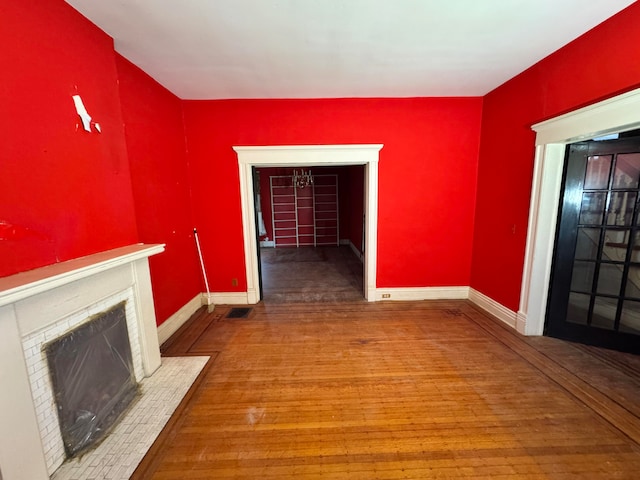 unfurnished living room with wood-type flooring and a brick fireplace