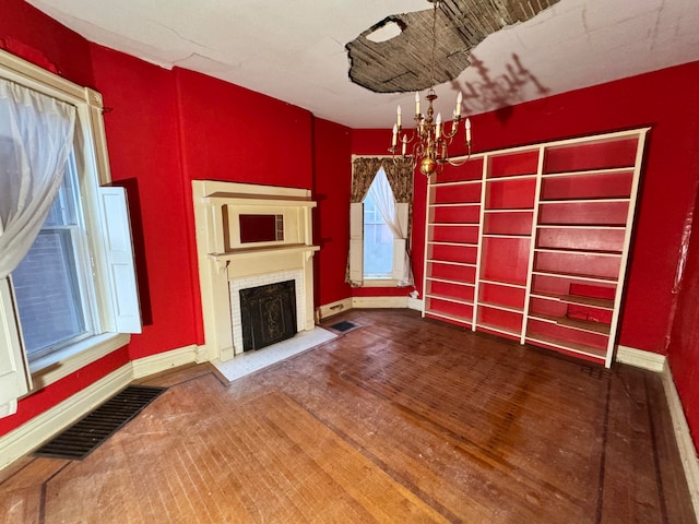 unfurnished living room featuring a notable chandelier, wood-type flooring, and a fireplace