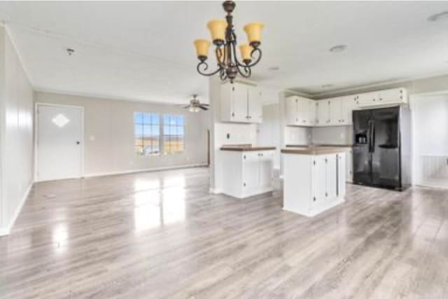 kitchen with black refrigerator with ice dispenser, ceiling fan with notable chandelier, light wood-type flooring, a kitchen island, and white cabinetry