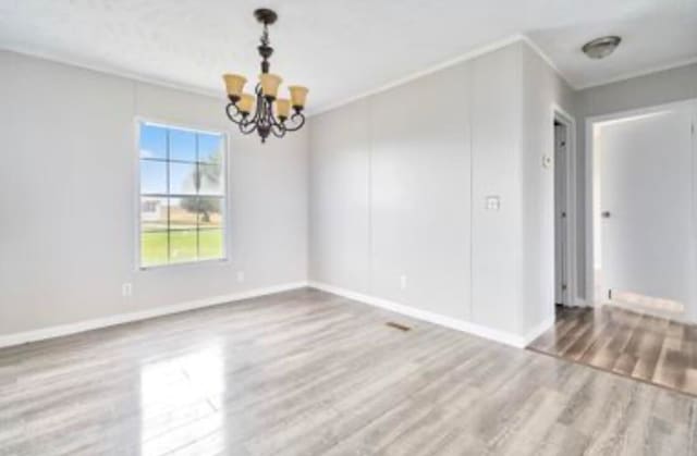 unfurnished room featuring ornamental molding, wood-type flooring, and an inviting chandelier