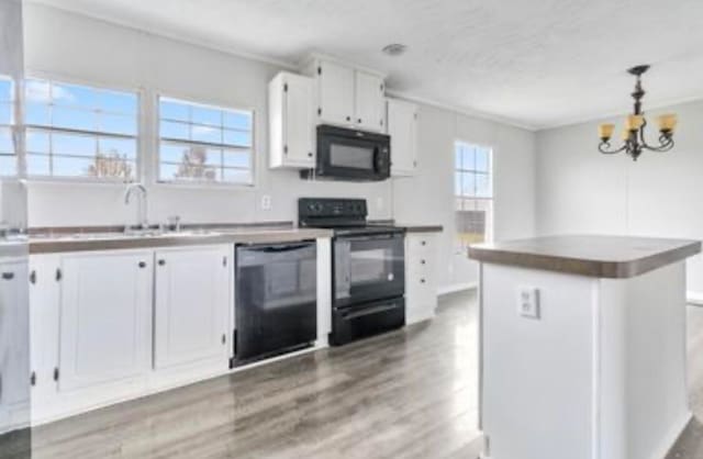 kitchen featuring black appliances, a center island, a healthy amount of sunlight, and white cabinets