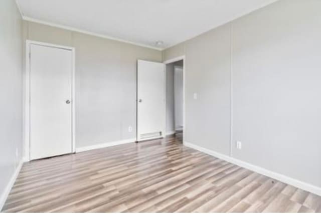 unfurnished bedroom with light hardwood / wood-style floors and ornamental molding