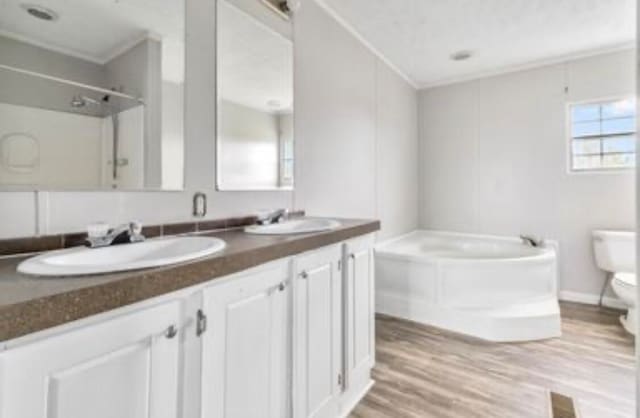 bathroom featuring a washtub, vanity, crown molding, hardwood / wood-style floors, and toilet