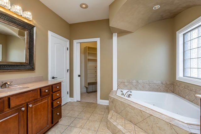 bathroom featuring tile patterned flooring, vanity, and a relaxing tiled tub