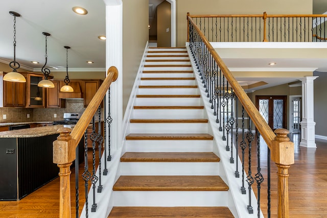 stairway featuring hardwood / wood-style floors, ornate columns, and crown molding