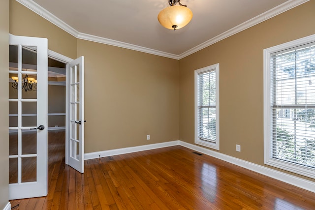 unfurnished room featuring french doors, hardwood / wood-style flooring, crown molding, and a notable chandelier