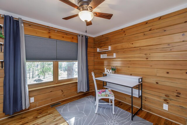 office space with ceiling fan, wooden walls, and hardwood / wood-style flooring