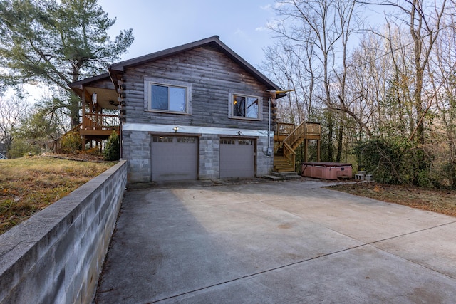 view of property exterior with a garage, a hot tub, and a wooden deck