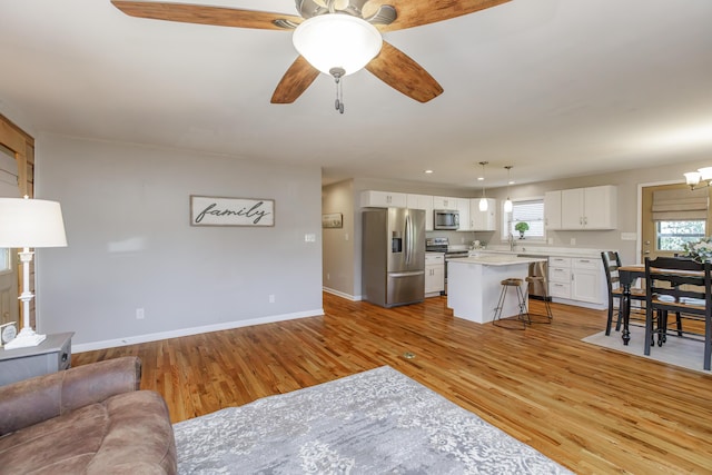 living room featuring sink, ceiling fan with notable chandelier, and light hardwood / wood-style floors