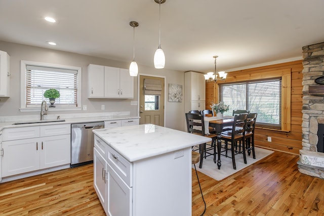 kitchen featuring dishwasher, a center island, sink, white cabinetry, and hanging light fixtures