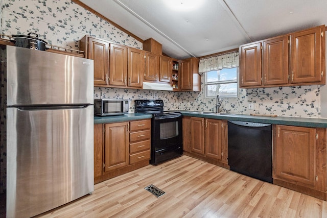 kitchen featuring brown cabinets, dark countertops, vaulted ceiling, a sink, and black appliances