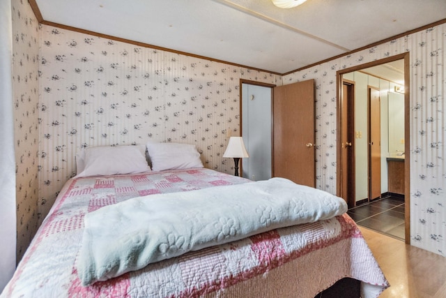 bedroom with crown molding, tile patterned floors, ensuite bath, and wallpapered walls