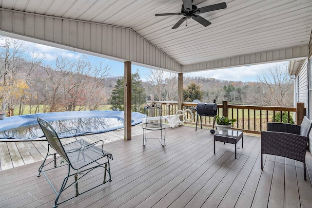 deck featuring a ceiling fan, a grill, a mountain view, and a wooded view