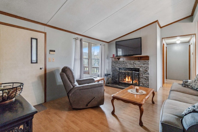 living room featuring vaulted ceiling, a stone fireplace, crown molding, and light hardwood / wood-style flooring