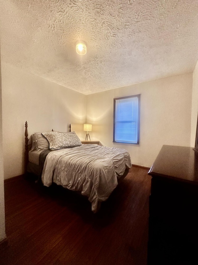 bedroom with dark hardwood / wood-style flooring and a textured ceiling