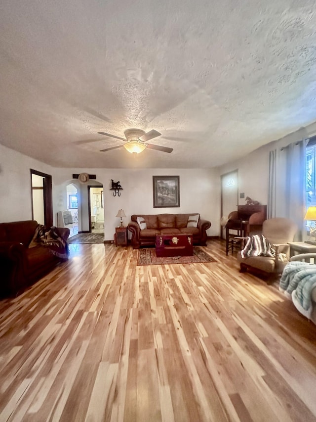 living room with ceiling fan, light hardwood / wood-style floors, and a textured ceiling