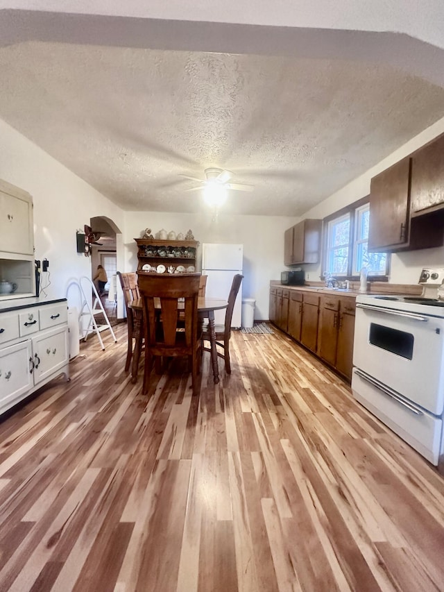 kitchen featuring a textured ceiling, ceiling fan, light hardwood / wood-style flooring, and white appliances