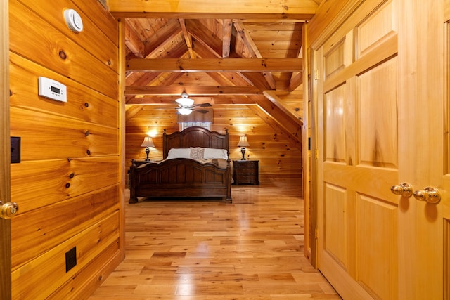 bedroom with vaulted ceiling with beams, light hardwood / wood-style floors, wooden ceiling, and wooden walls