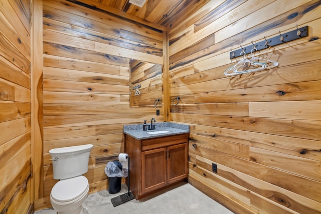 bathroom with vanity, wood walls, and toilet