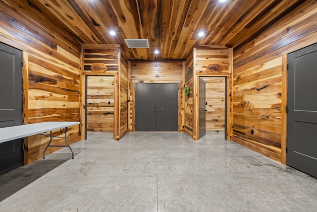 hallway with wood walls, concrete floors, and wooden ceiling