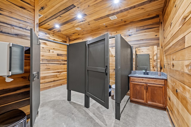 interior space featuring wood walls, vanity, wooden ceiling, and toilet