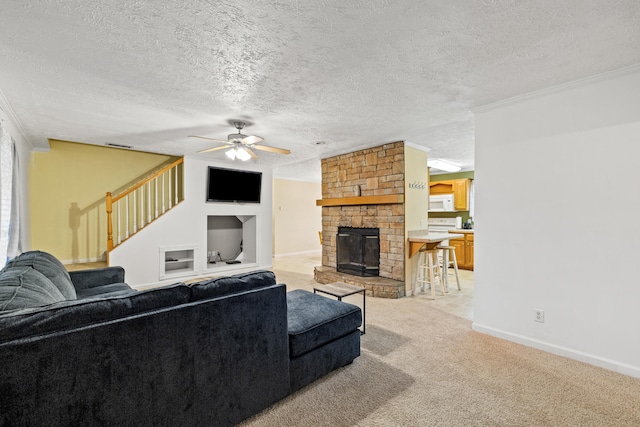 carpeted living room featuring a textured ceiling, a stone fireplace, ceiling fan, and ornamental molding