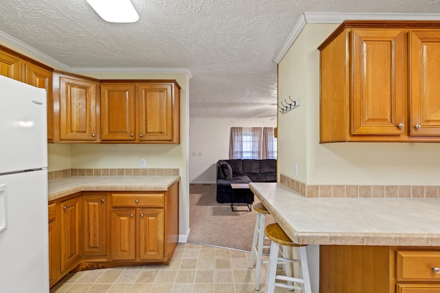 kitchen featuring a textured ceiling, white fridge, and ornamental molding